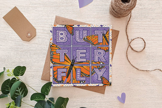 Purple and orange butterfly greeting card with a recycled kraft brown envelope, sat on a cream surface surrounded by brown twine and green vines