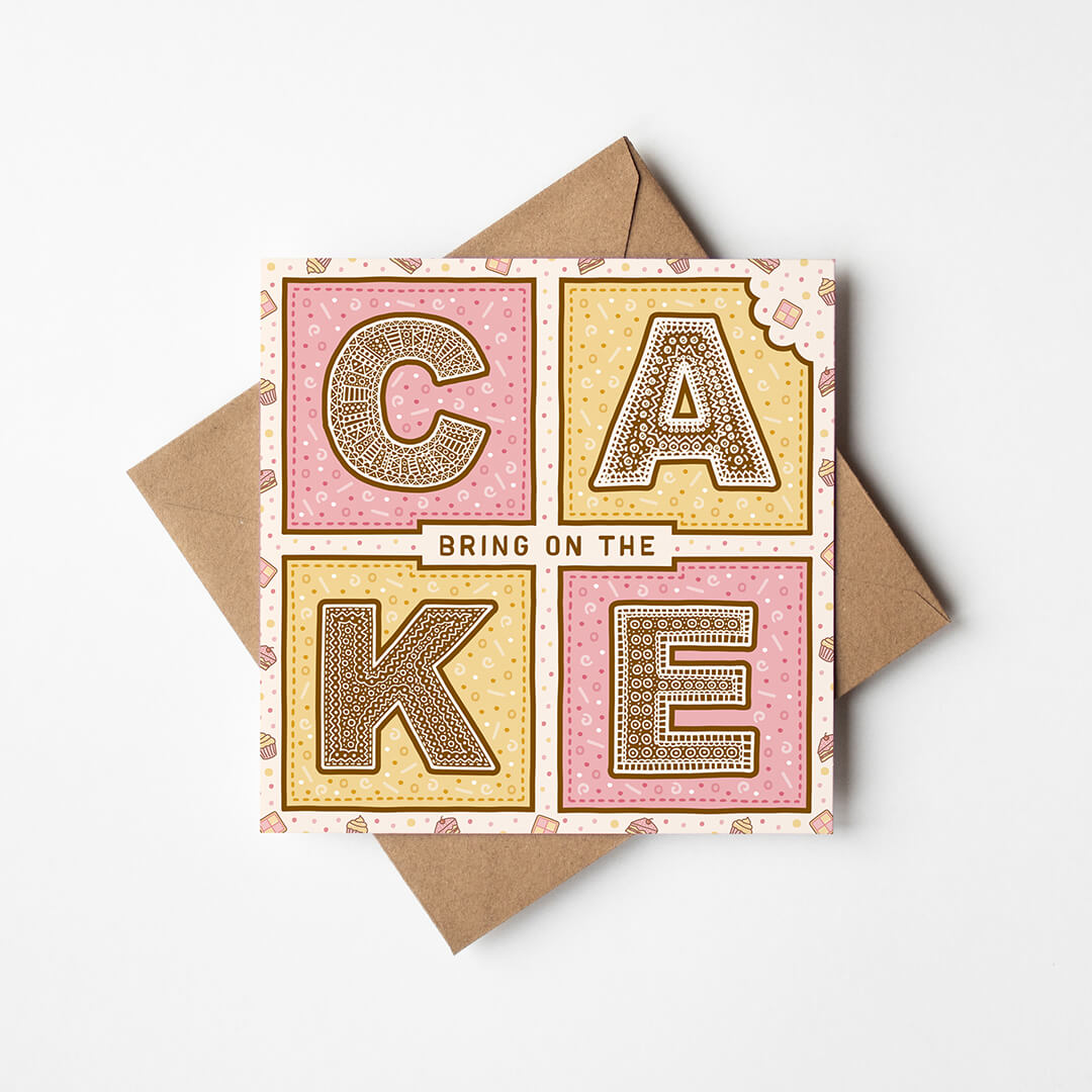 Pink and yellow birthday card with 'Bring On The Cake' text and kraft brown envelope on a white background