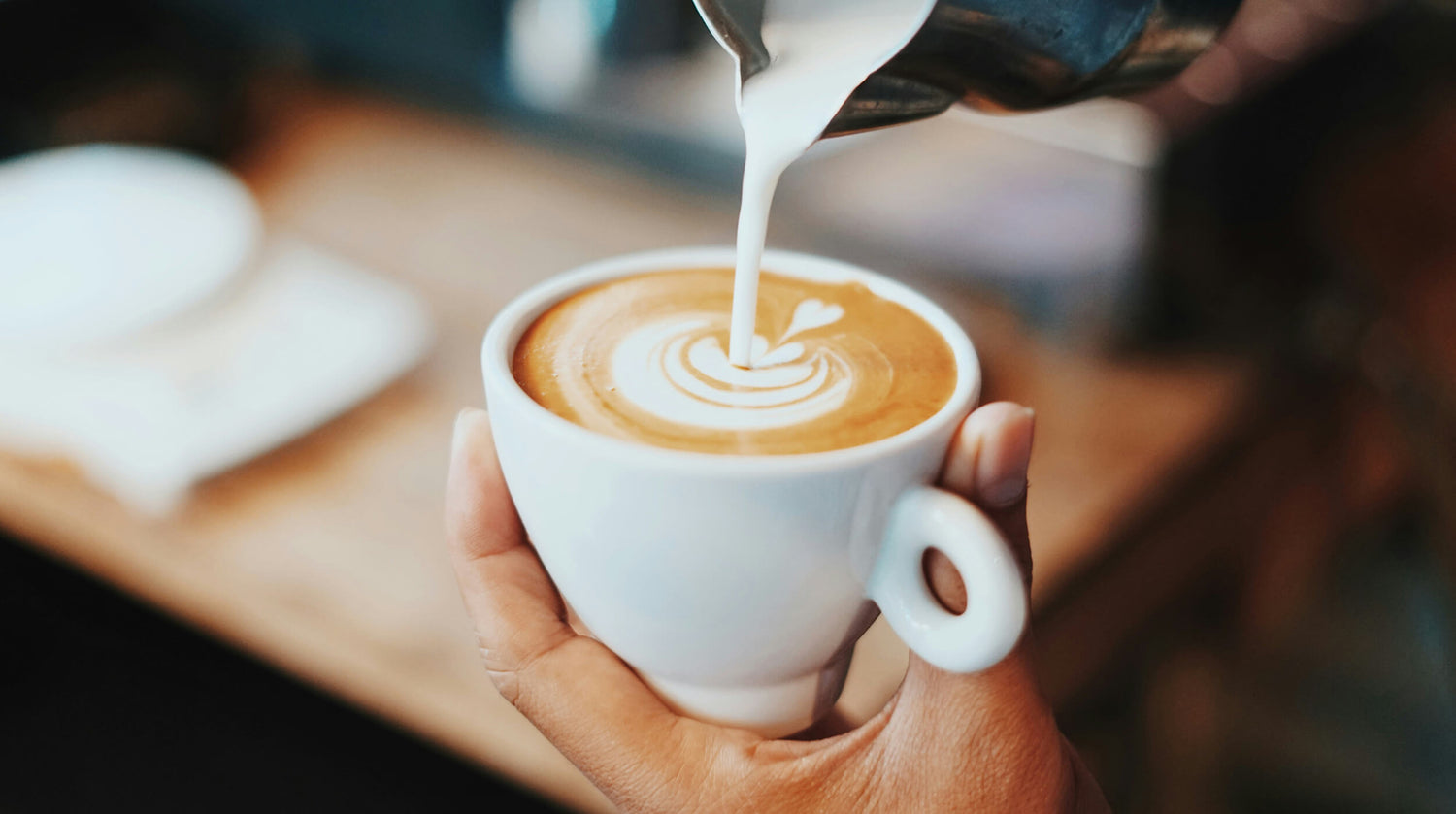 Coffee being poured into small white ceramic cup