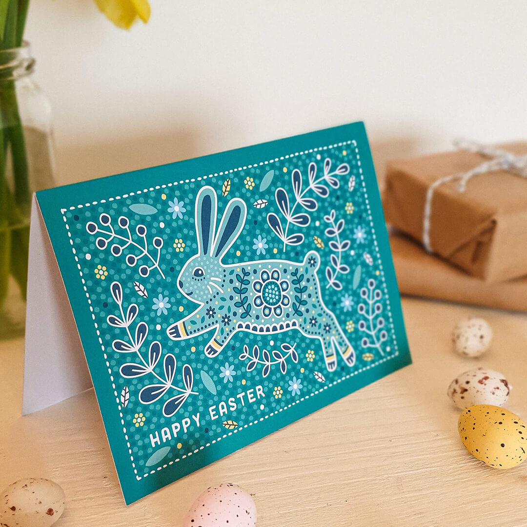 cute easter bunny card featuring hopping rabbit alongside floral and botanical illustrations in bright turquoise colour scheme