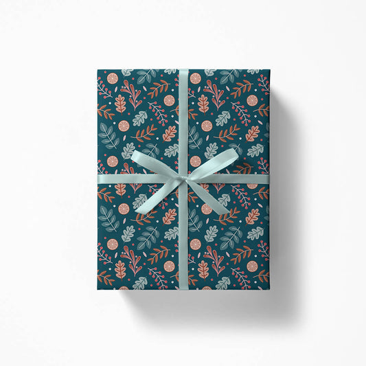 Gift box wrapped in botanical Christmas gift wrap and light blue ribbon on a white background