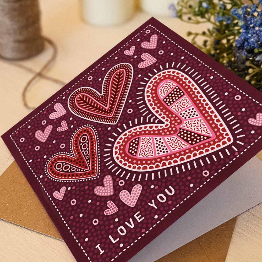 deep pink romantic anniversary card featuring folk-art inspired illustrated hearts and i love you message. Supplied with a recycled kraft brown envelope