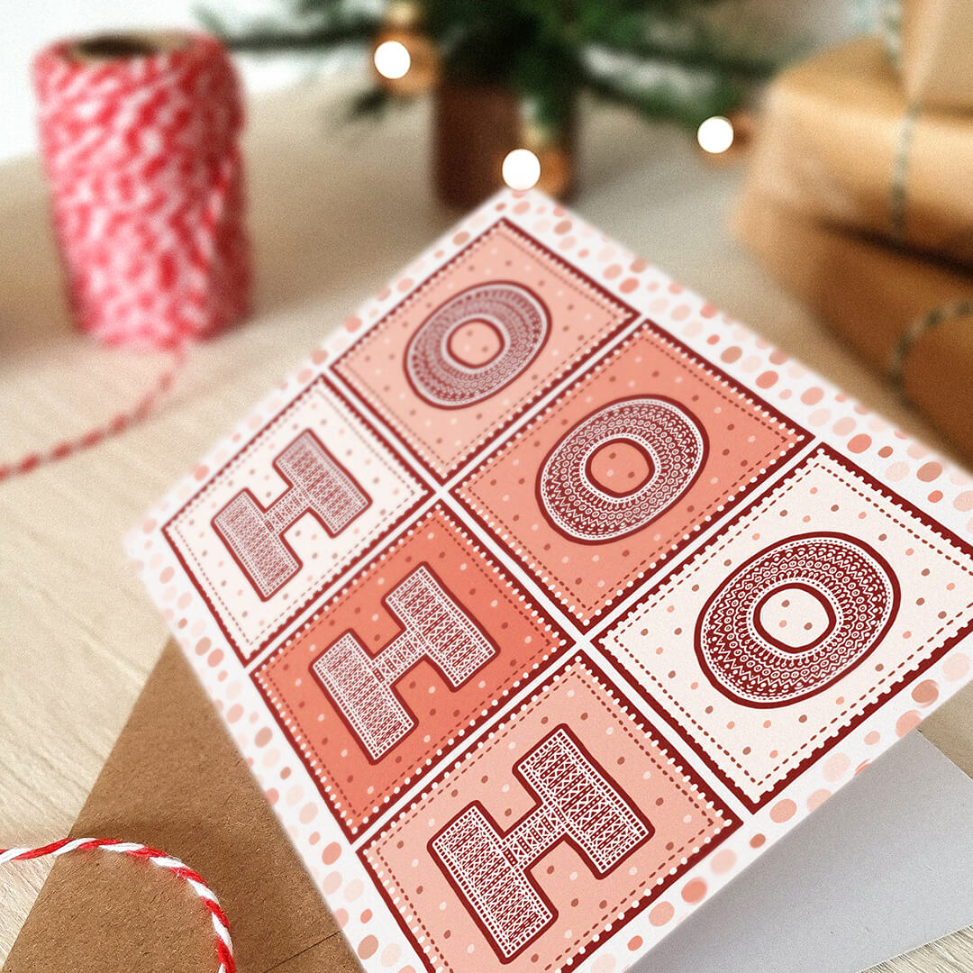 Red Ho Ho Ho Christmas Card with 'HO HO HO' text on a festive background with wrapped gifts and a Christmas tree.