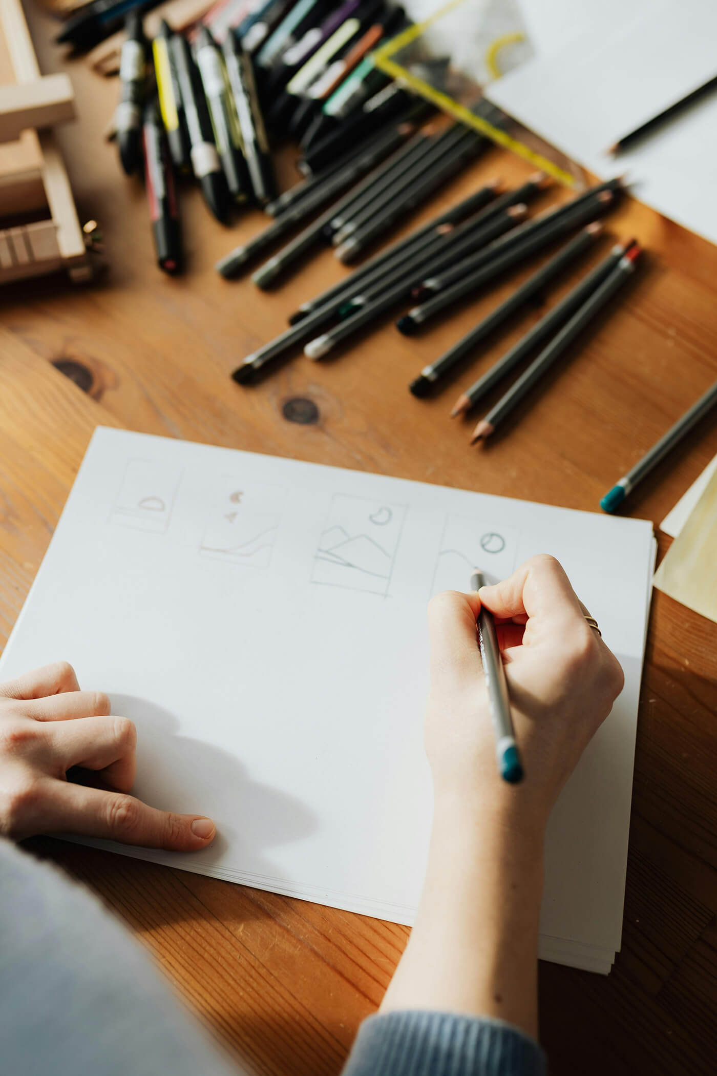 woman drawing in a sketchbook on a wooden table