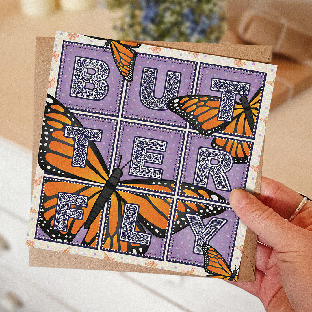 Butterfly greeting card with monarch butterfly illustrations and detailed typography on a purple background held by a hand