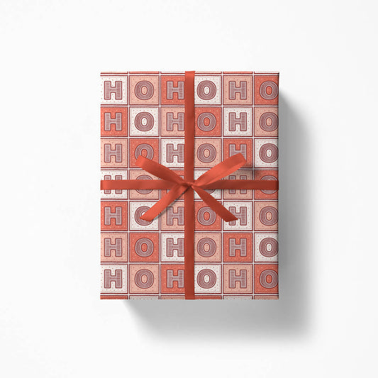Gift box with 'HO HO HO' Christmas gift wrap and red ribbon on a white background