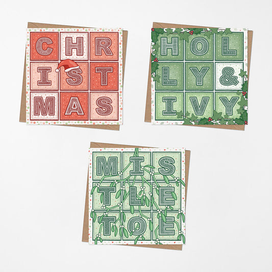 Three traditional red and green typographic Christmas cards with kraft brown envelopes on a white background.
