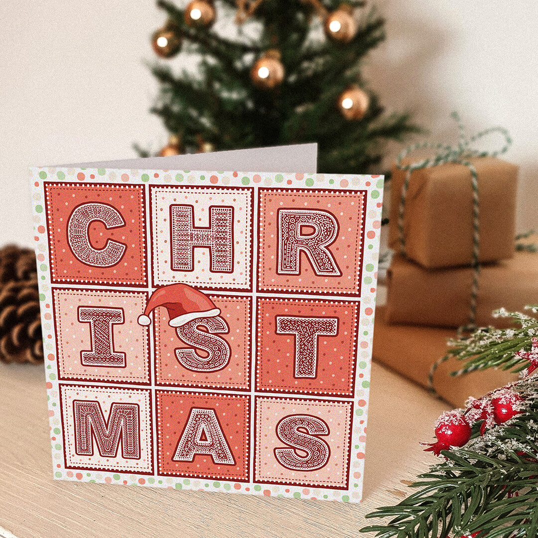 Red Christmas card with 'CHRISTMAS' text and a Santa hat illustration in front of a Christmas tree and presents.