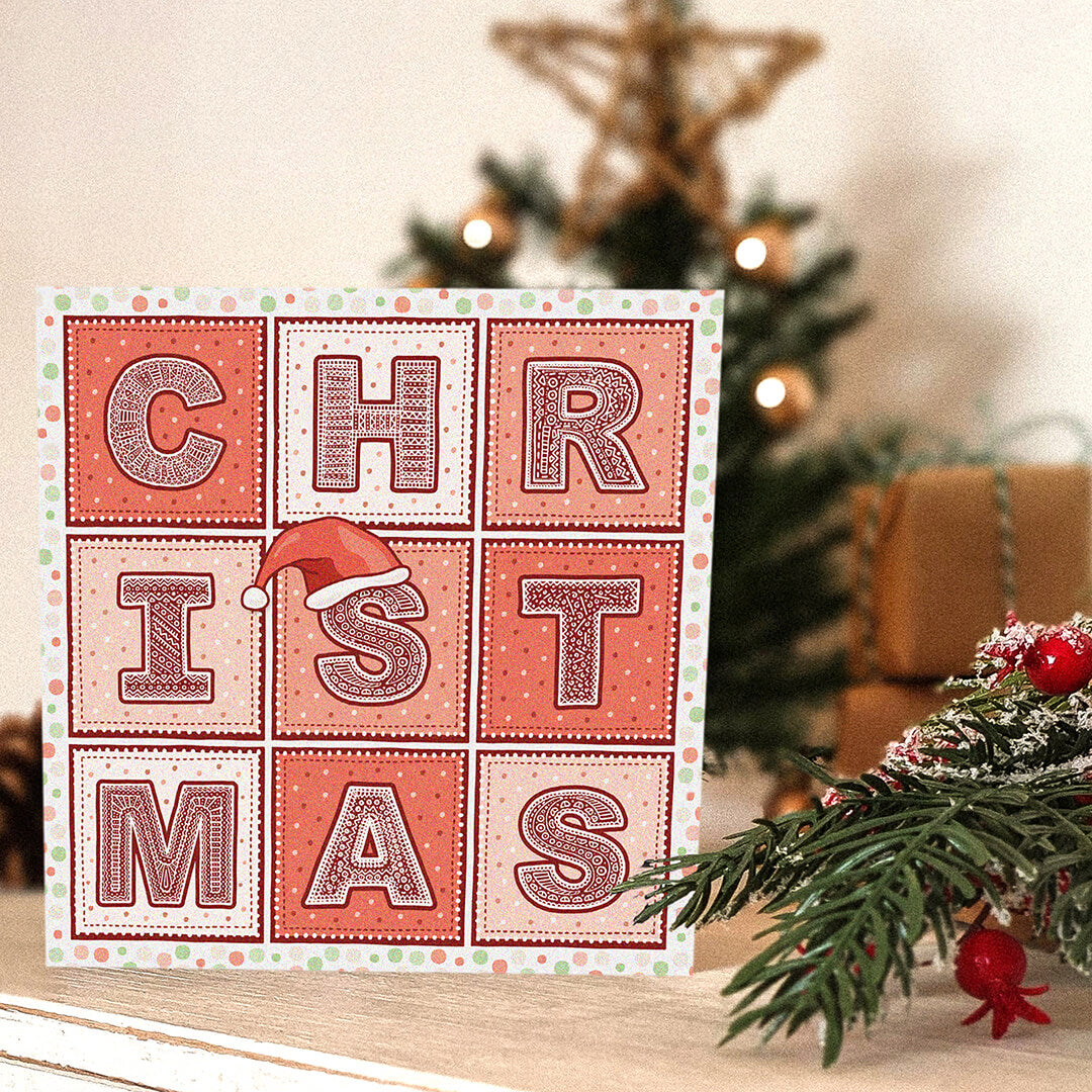 Red Christmas card with 'Christmas' text and a Santa hat illustration in front of a Christmas tree.