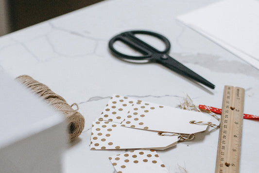 Worktop with Christmas cards, brown natural twine, scissors, gift tags, and ruler and pencil