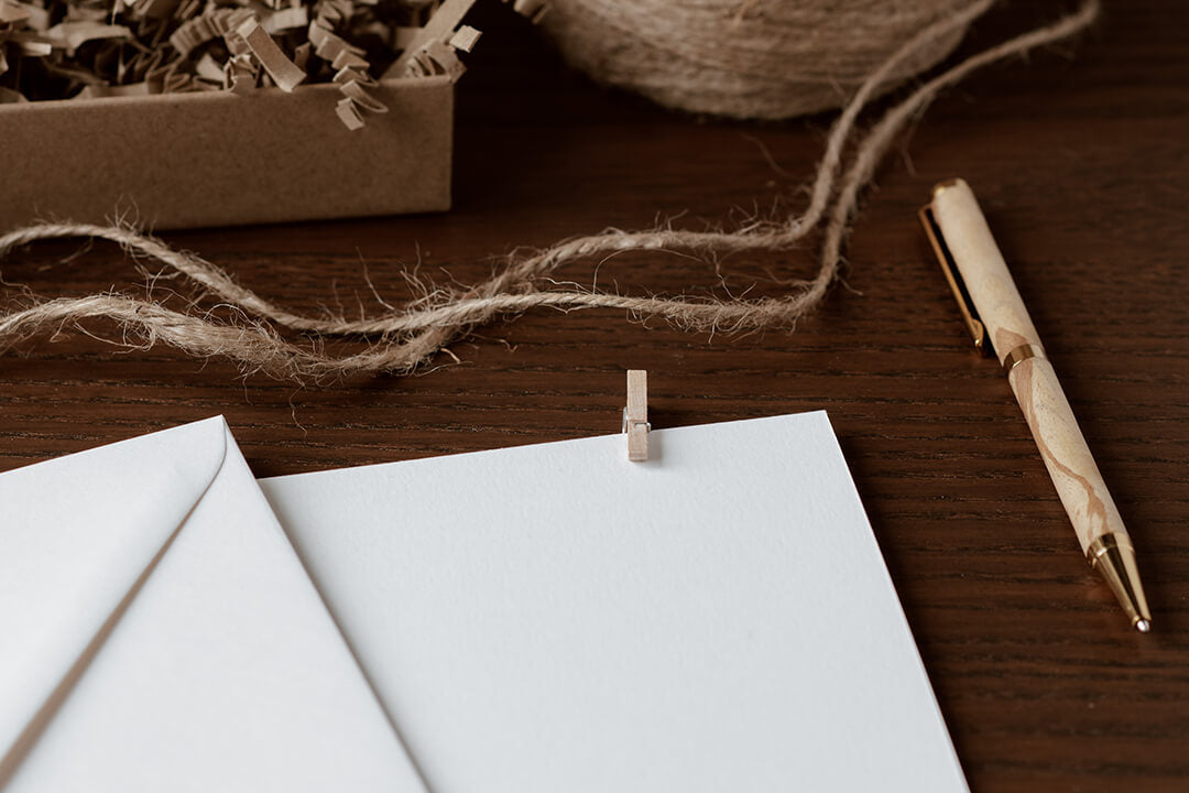 Things you should look out for when buying eco-friendly stationery. Desk with envelope, paper, pen, brown twine and cardboard packaging