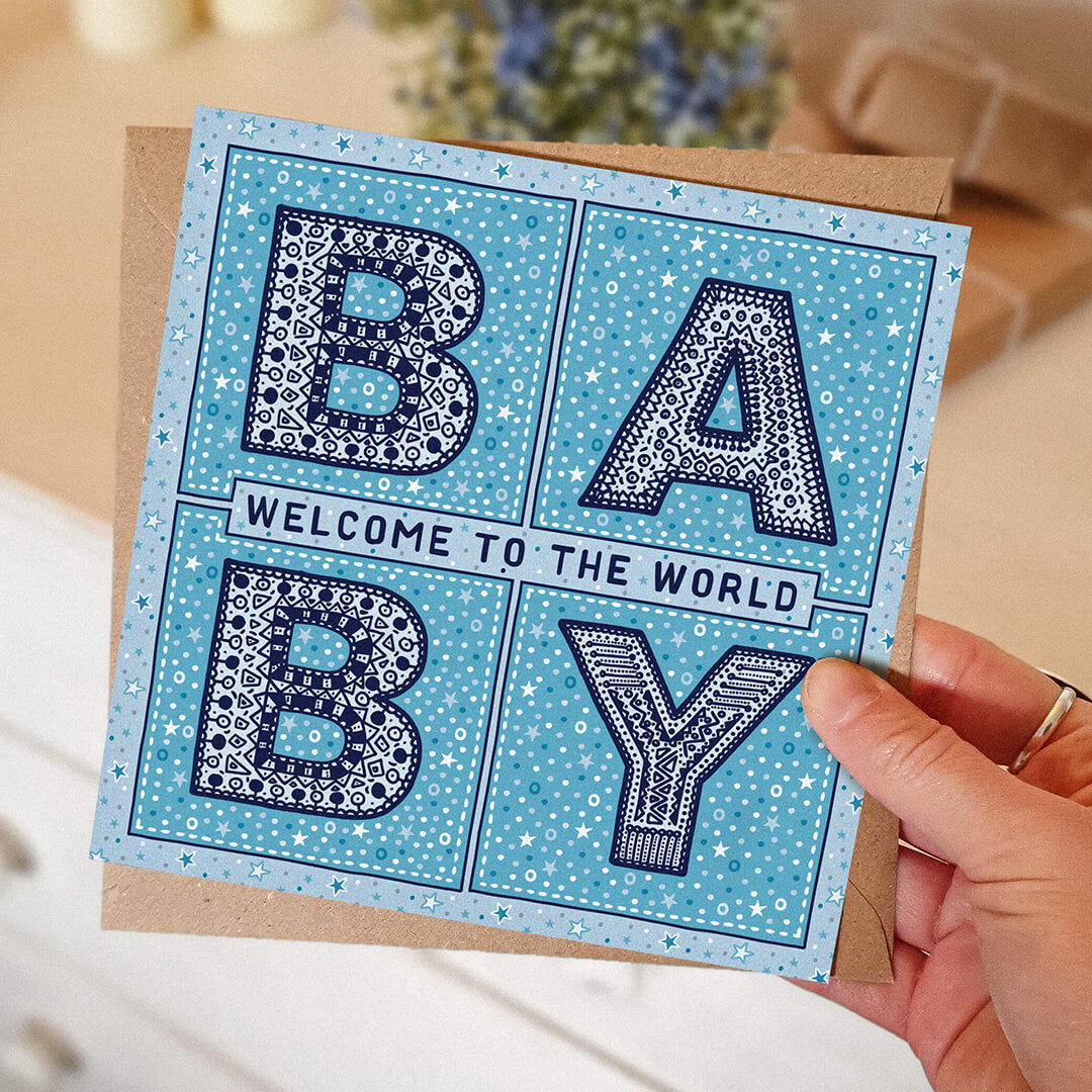 hand holding unique blue new baby card Welcome to the world baby Kraft brown recycled envelope Blank inside