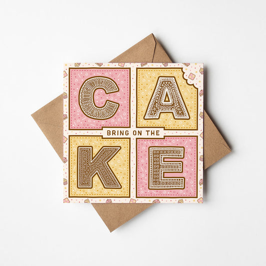 Pink and yellow birthday card with 'Bring On The Cake' text and kraft brown envelope on a white background
