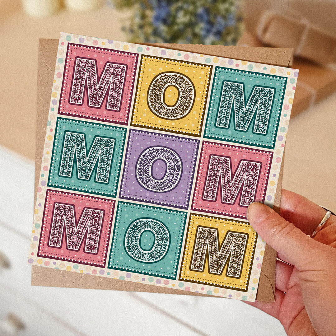 Colourful Mother's Day card with 'MOM' message held by a hand