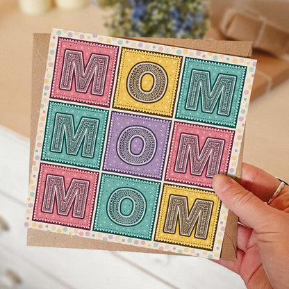 Colourful Mother's Day card with 'MOM' message held by a hand