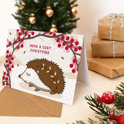 Christmas card with hedgehog design and 'Have a Cosy Christmas' message, surrounded by festive decor.