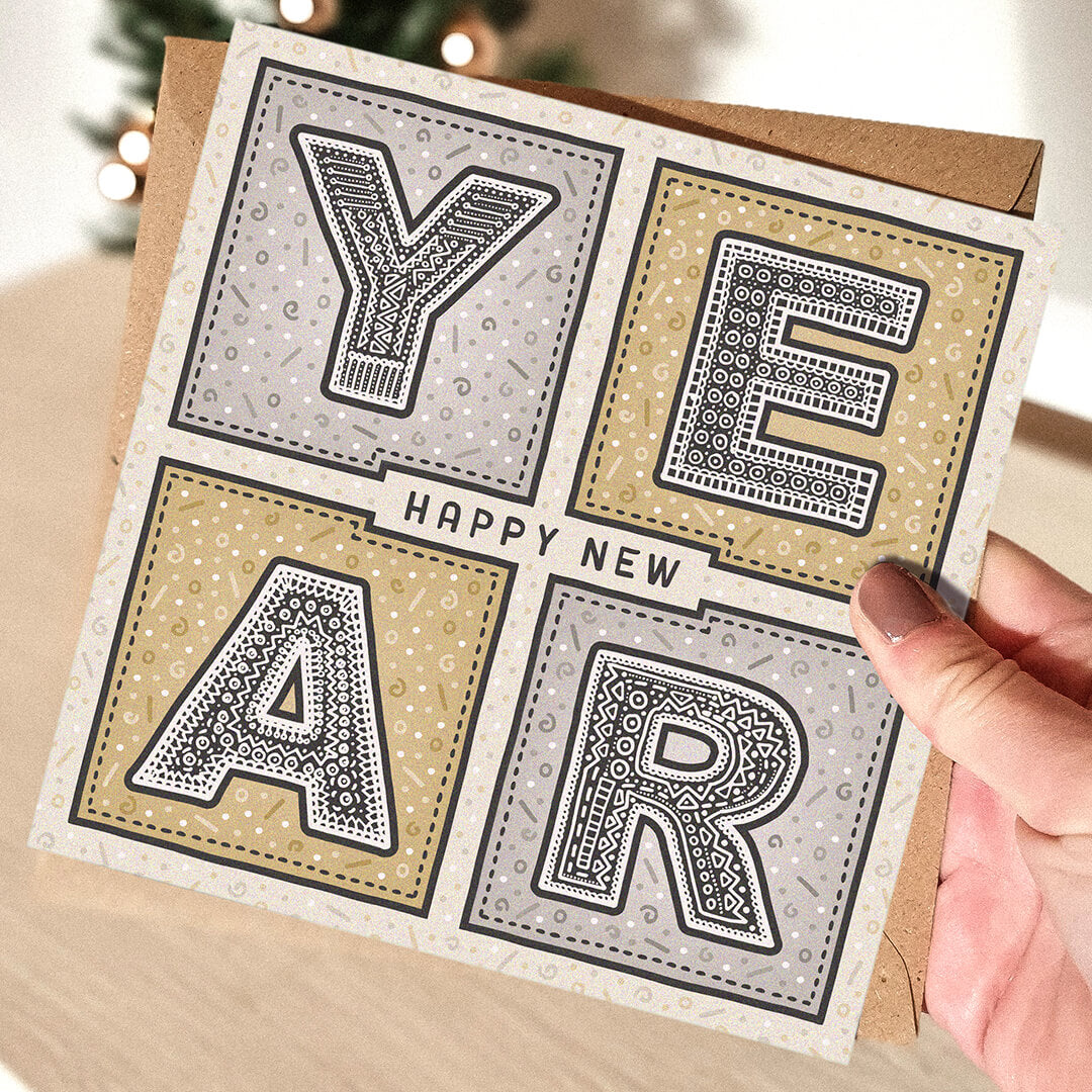 Hand holding a unique Happy New Year card with decorative lettering.