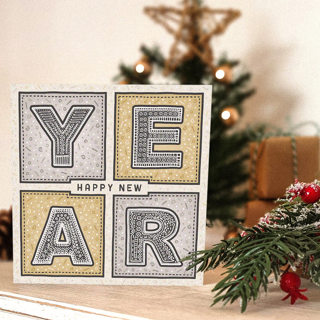 Gold and silver New Year card with decorative text in front of a Christmas tree