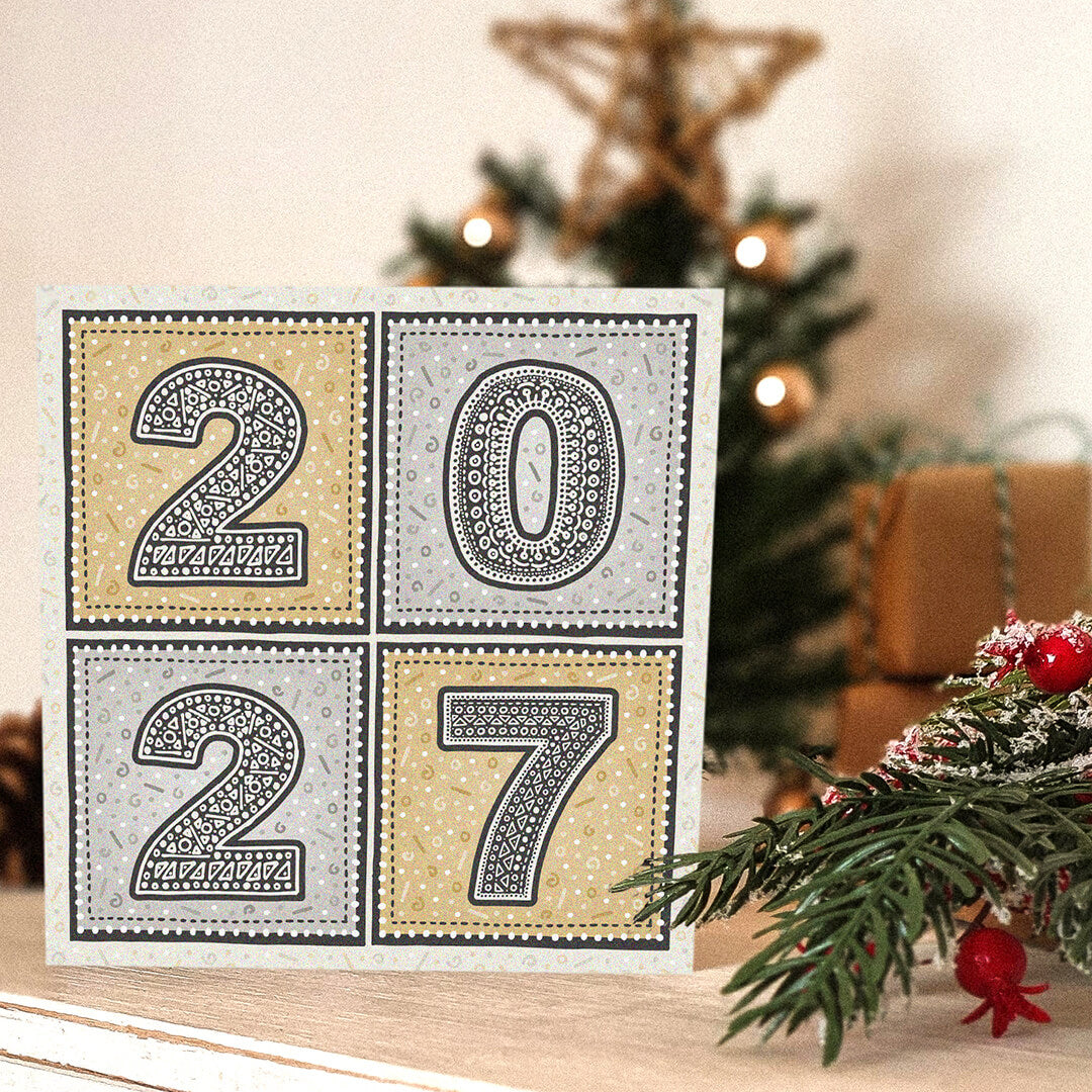 unique gold and silver 2027 new year card with blurred christmas tree in the background