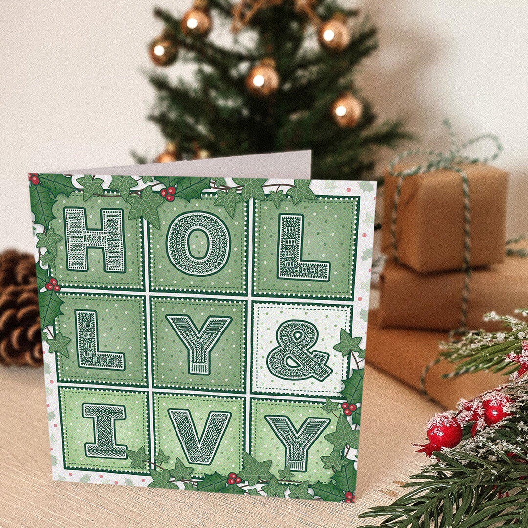 Holly & Ivy Christmas card with 'Holly & Ivy' design in front of a decorated Christmas tree and presents.
