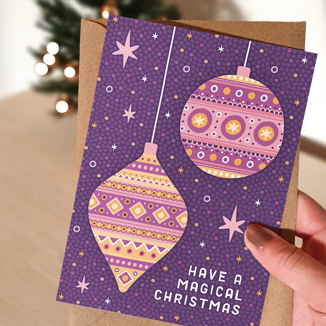 Hand holding illustrated purple baubles Christmas card Modern purple Christmas card Printed on FSC certified card Supplied with kraft brown recycled envelope