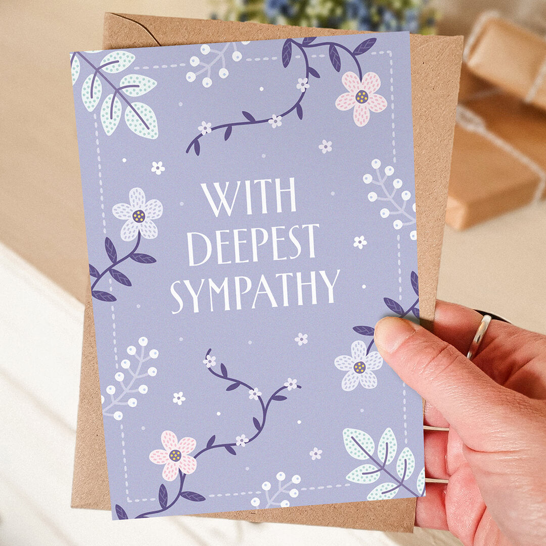 hand holding lilac floral sympathy card with blurred background