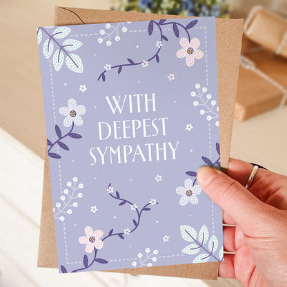 hand holding lilac floral sympathy card with blurred background