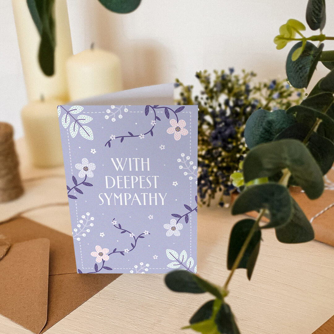 lilac floral sympathy card sat on a white dresser with candles and plants in the background