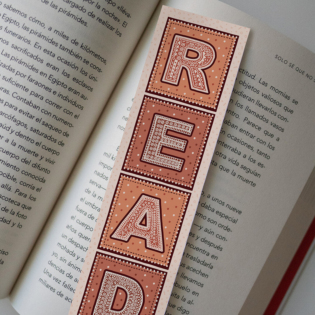 lifestyle shot of unique reading list bookmark featuring intricate typographic illustration of the word READ Printed on recycled card