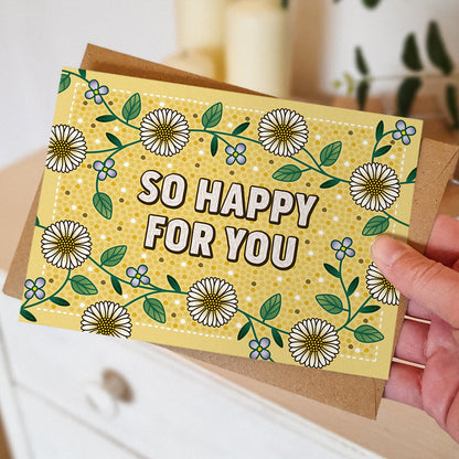 Hand holding yellow floral congratulations card with so happy for you message Unique so happy for you card Blank inside Recycled kraft brown envelope