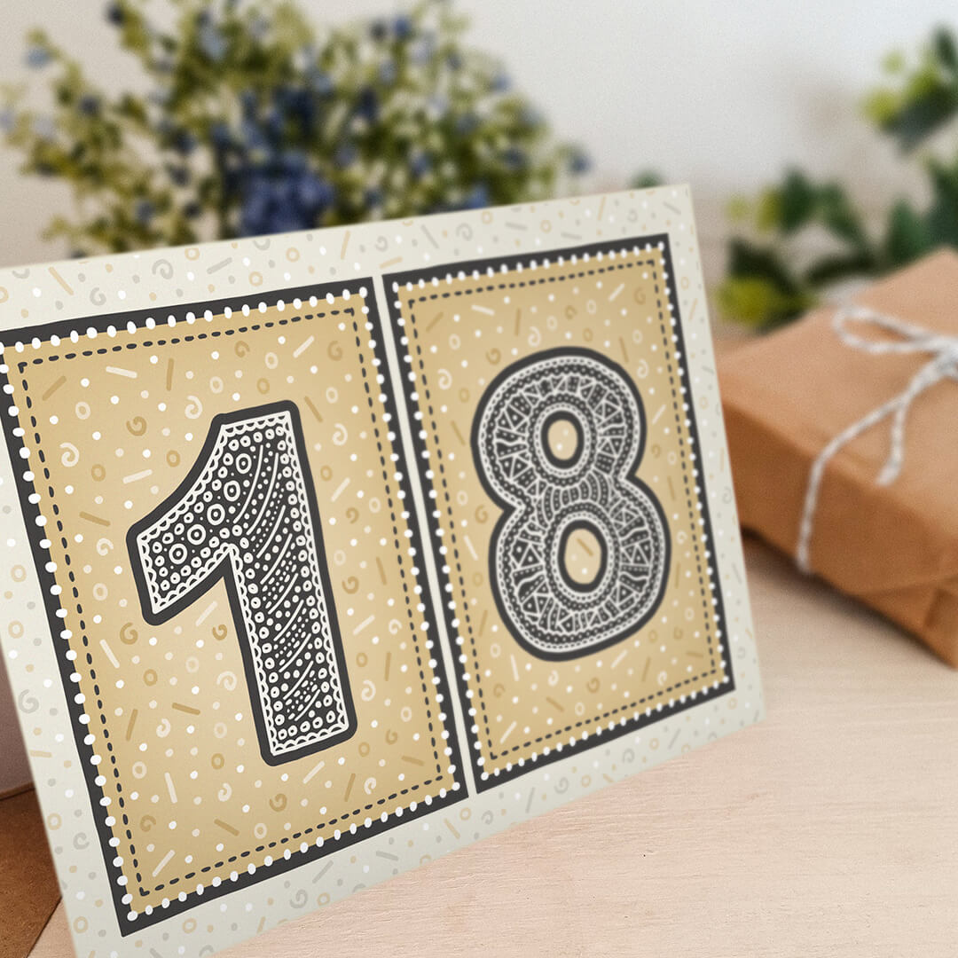 unique gold 18th birthday card with flowers and gifts wrapped in kraft brown paper in the background