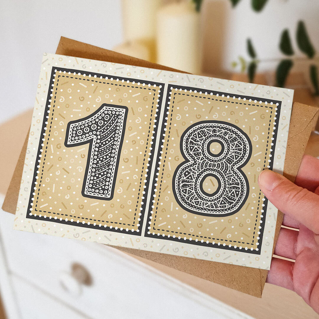 hand holding unique black and gold 18th birthday card with blurred background