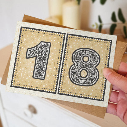 hand holding unique black and gold 18th birthday card with blurred background