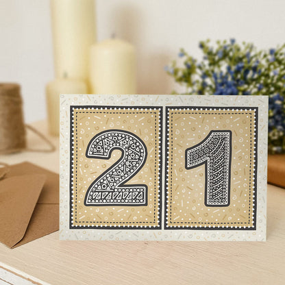 unique black and gold 21st birthday card with flowers and candles blurred in the background