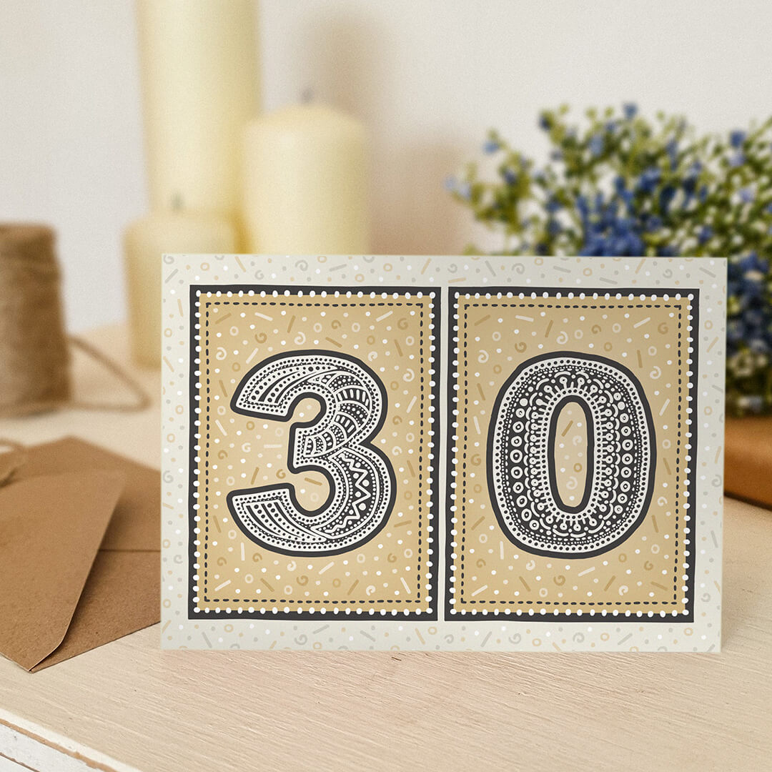 unique gold 30th birthday card with candles and flowers blurred in the background