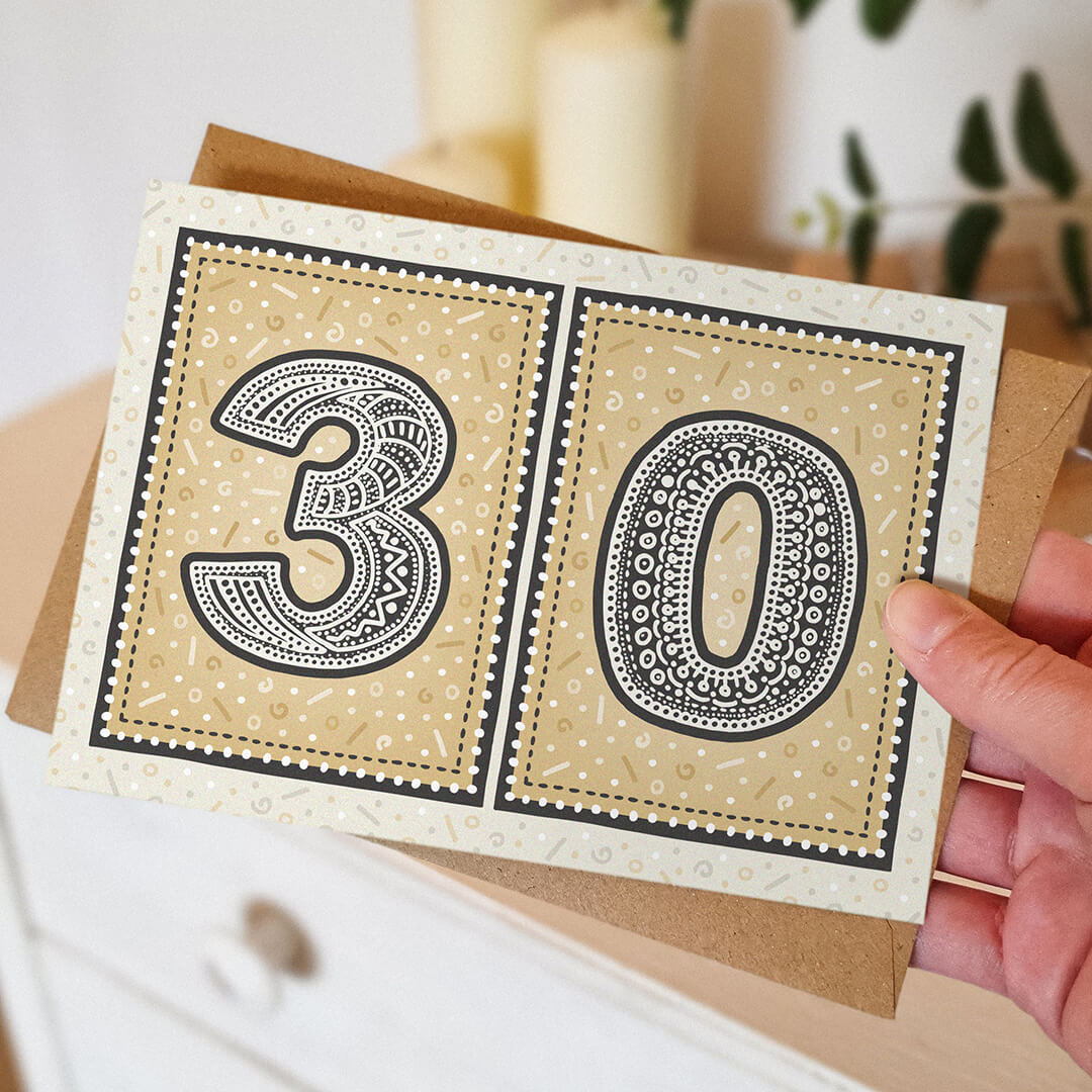 hand holding unique black and gold 30th birthday card with blurred background