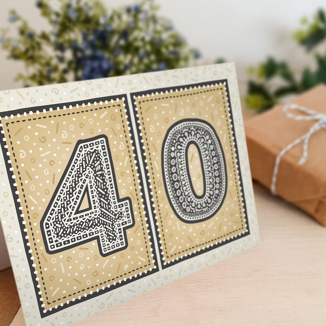 unique black and gold 40th birthday card with flowers and gifts in background