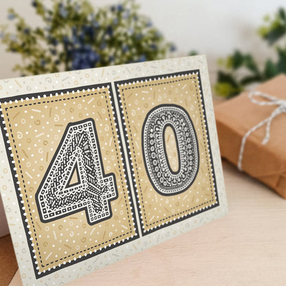 unique black and gold 40th birthday card with flowers and gifts in background