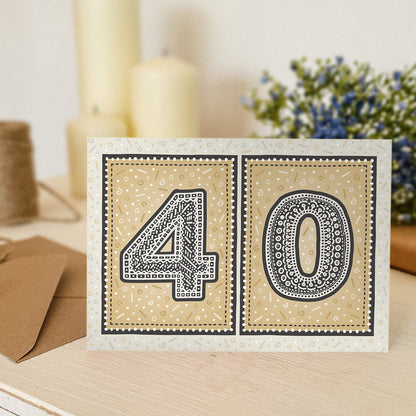unique gold 40th birthday card with candles and flowers blurred in background