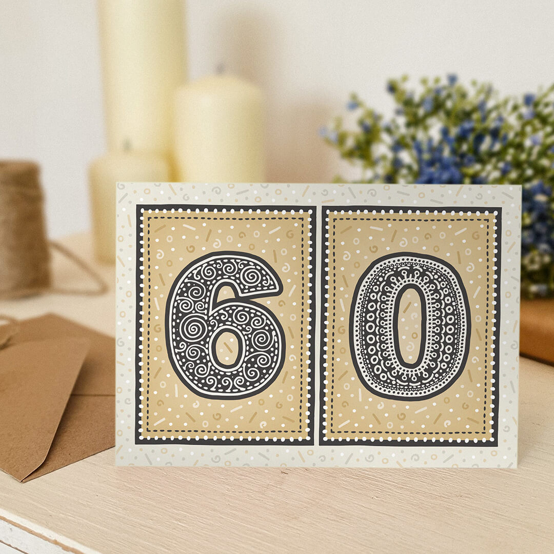 unique gold 60th birthday card with candles and flowers blurred in the background