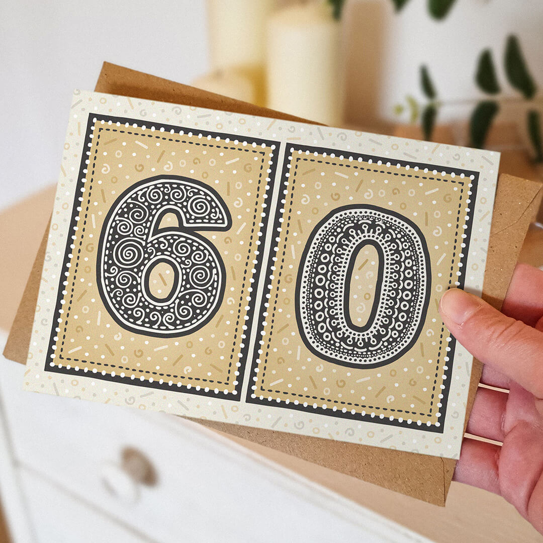 hand holding unique gold 60th birthday card with blurred background