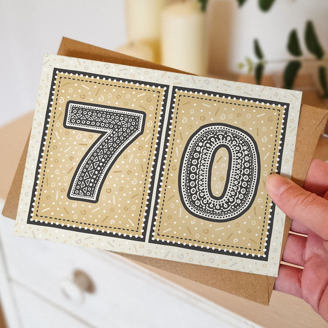 hand holding unique gold 70th birthday card with blurred background