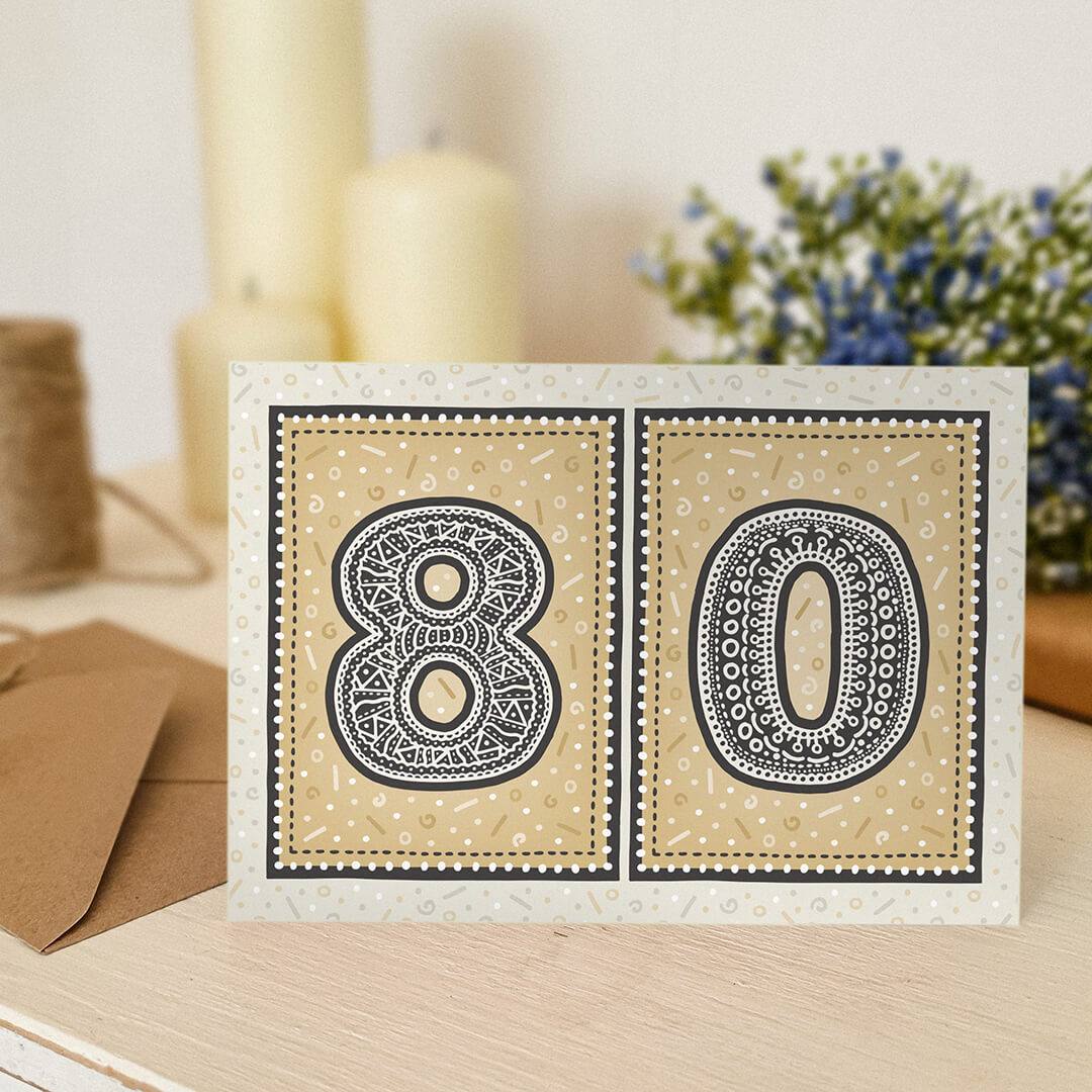 unique gold 80th birthday card with candles and flowers blurred in the background
