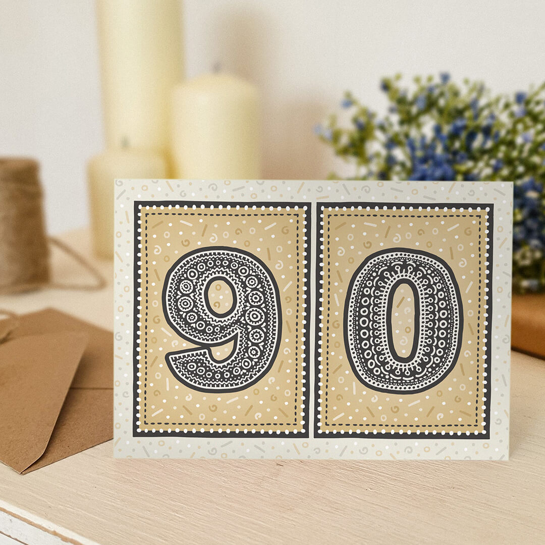 unique gold 90th birthday card with candles and flowers blurred in the background