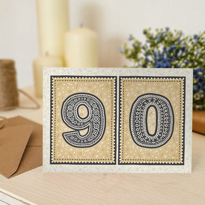 unique gold 90th birthday card with candles and flowers blurred in the background