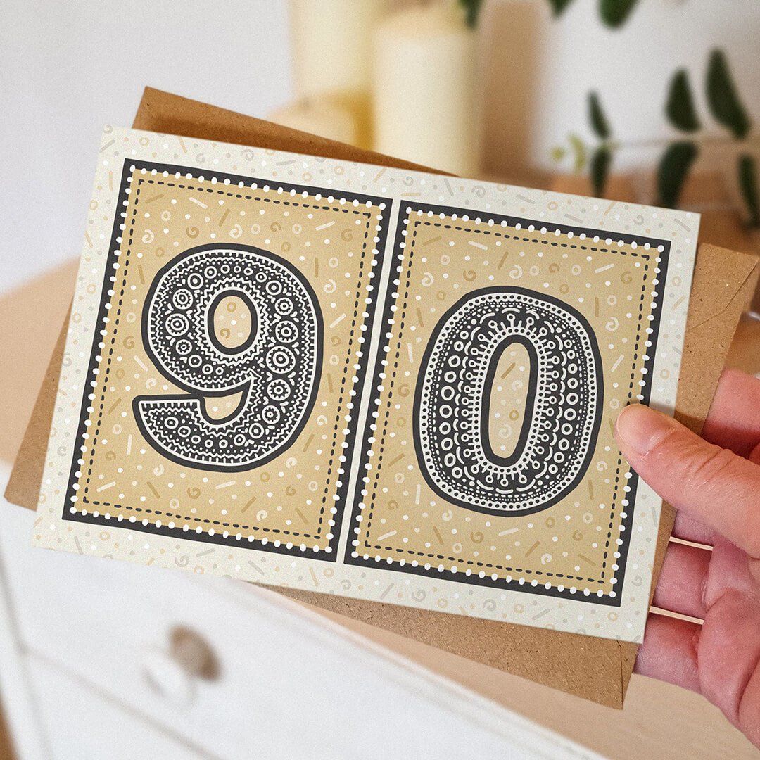 hand holding unique gold 90th birthday card with blurred background