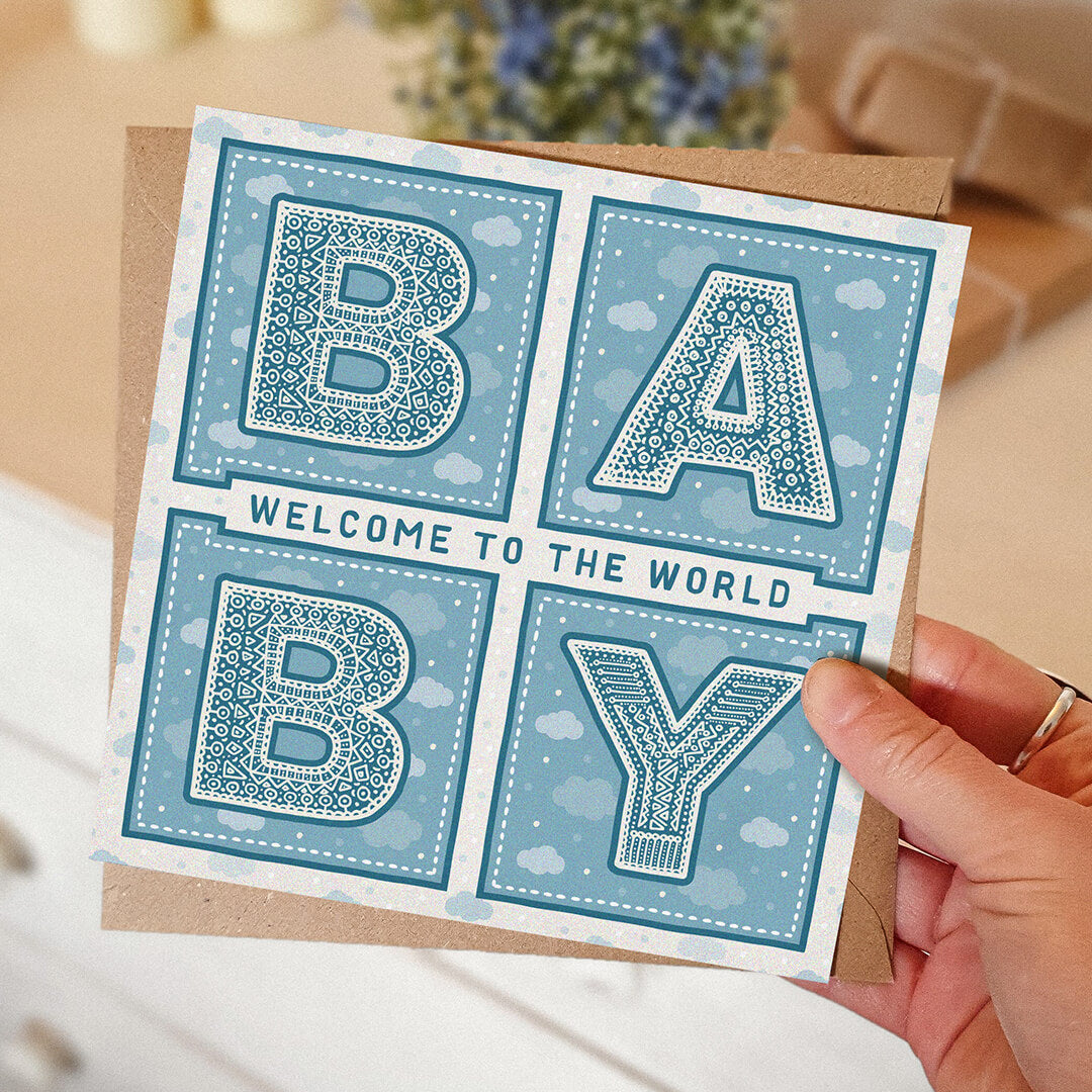 hand holding unique blue new baby card Welcome to the world baby Kraft brown recycled envelope Blank inside