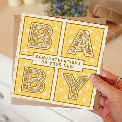 hand holding yellow gender neutral new baby card Congratulations on your new baby card Printed on fsc-certified card Blank inside