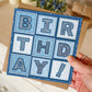 Hand holding unique birthday card for him Blue background with hand drawn lettering spelling BIRTHDAY! Printed on recycled card Supplied with kraft brown recycled envelope