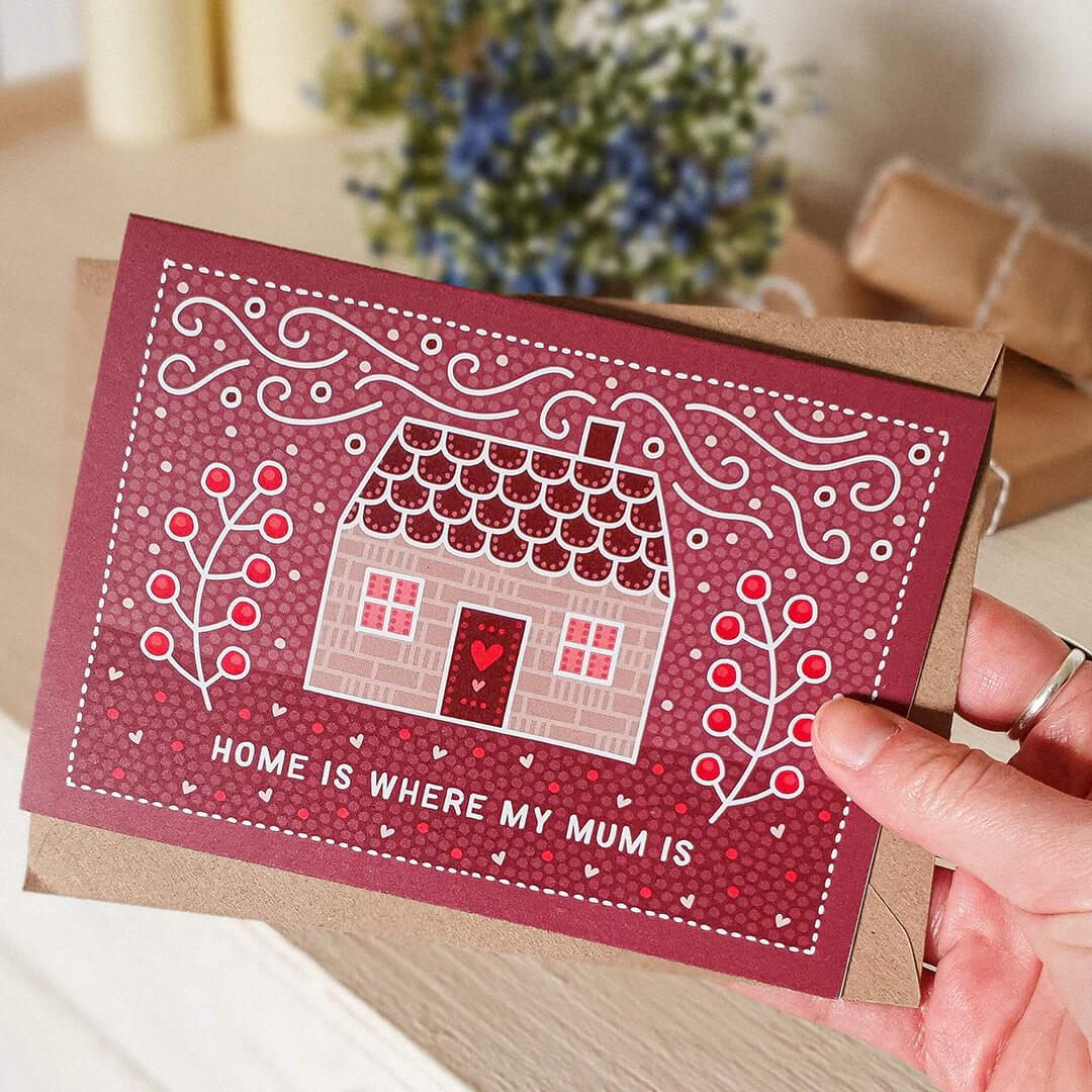 Hand holding Home Is Where My Mum Is beautiful Mother's Day card Unique cute pink home illustration Printed on recycled card Supplied with kraft brown recycled envelope